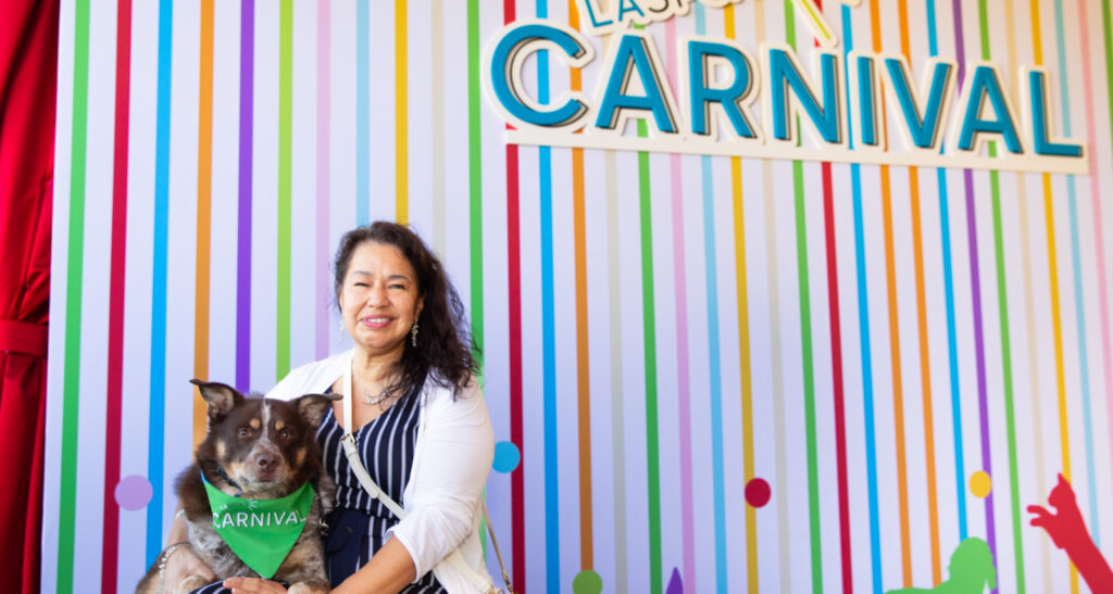 A woman with dark hair poses at Carnival with her dog